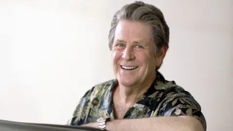 Getty Images Brian Wilson pictured with one arm leaning on a piano in the early 2000s