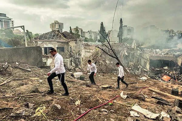 People walk near the ruins of buildings after Iranian strike in Rehovot, Israel