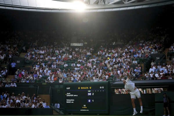 Jack Draper of Britain serves to Sebastian Baez of Argentina during their men's singles match at the Wimbledon Tennis Championships. (AP) Photos of Wimbledon fans and players struggling to stay cool in record-breaking heat